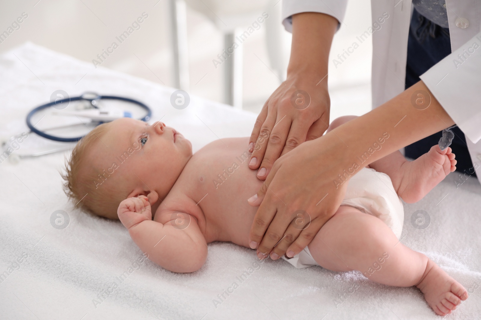 Photo of Doctor examining cute baby indoors, closeup. Health care