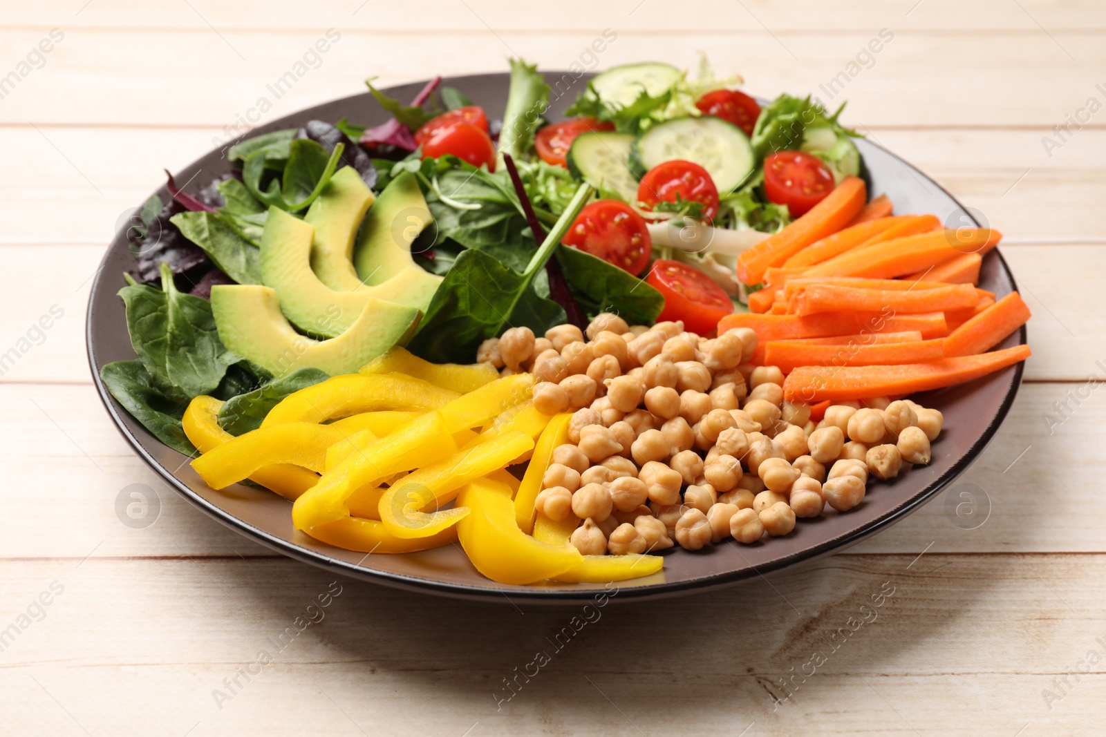 Photo of Balanced diet and vegetarian foods. Plate with different delicious products on wooden table, closeup