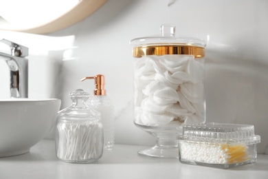 Cotton swabs and pads on white countertop in bathroom