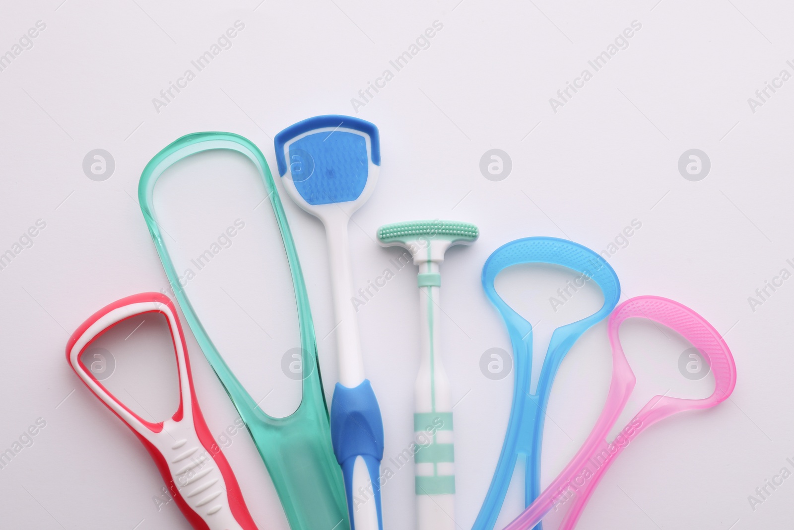 Photo of Different tongue cleaners on white background, top view