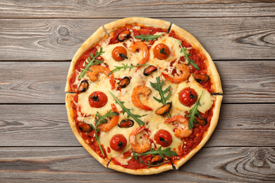 Delicious seafood pizza on wooden table, top view