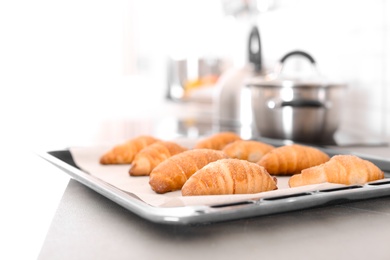 Photo of Oven sheet with freshly baked croissants on kitchen counter