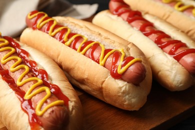 Photo of Delicious hot dogs with mustard and ketchup on wooden table, closeup