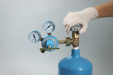 Photo of Medical worker checking oxygen tank on light grey background, closeup