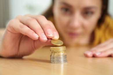 Photo of Closeup view of woman stacking coins at table, focus on hand