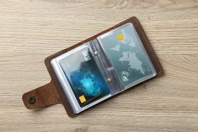 Photo of Leather card holder with credit cards on wooden table, top view