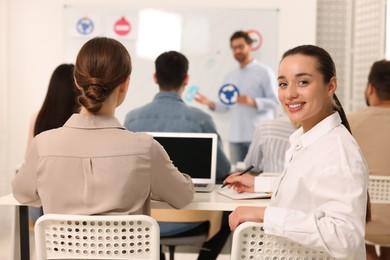 Happy woman at desk in class during lesson in driving school