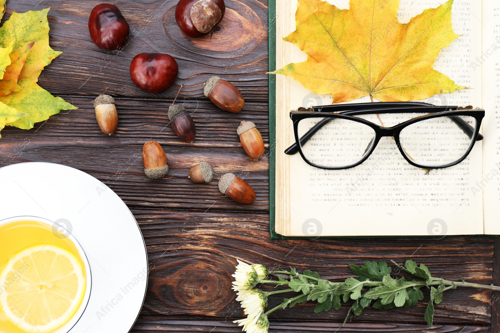 Photo of Maple leaves, book and cup of tea on wooden table, flat lay. Autumn atmosphere