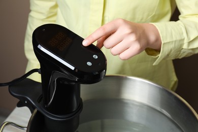 Photo of Sous vide cooking. Woman using thermal immersion circulator, closeup