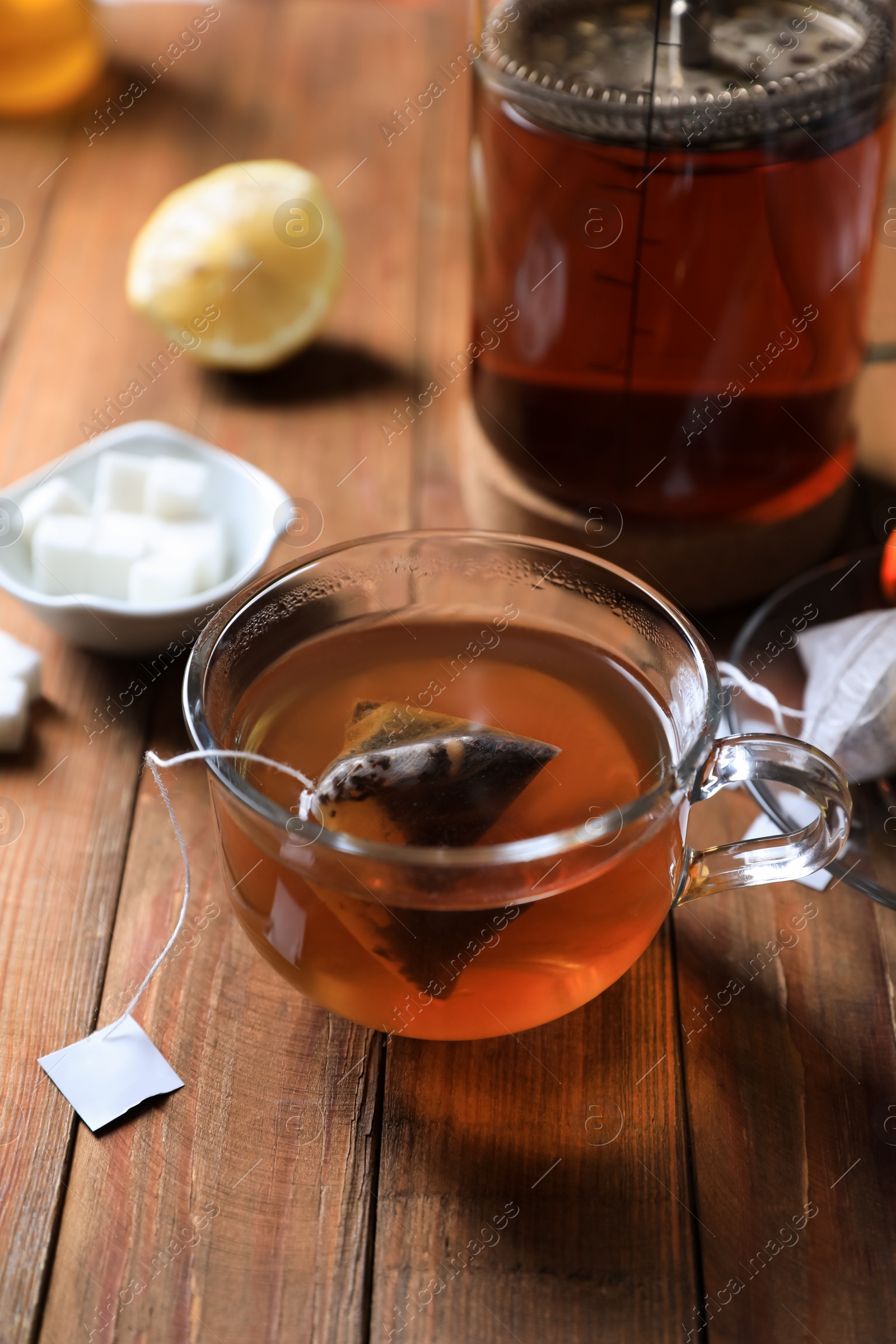 Photo of Tea bag in glass cup on wooden table