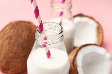 Photo of Delicious vegan milk and coconuts on pink background, closeup. Space for text
