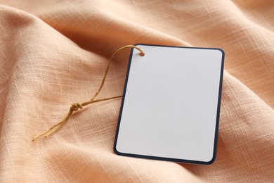 Photo of Cardboard tag with space for text on pale orange fabric, closeup