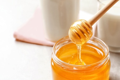 Photo of Honey pouring from dipper into jar, closeup