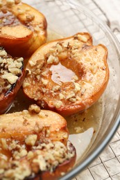 Photo of Delicious baked quinces with nuts and honey in bowl on table, closeup
