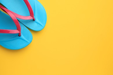 Photo of Stylish flip flops on yellow background, flat lay with space for text