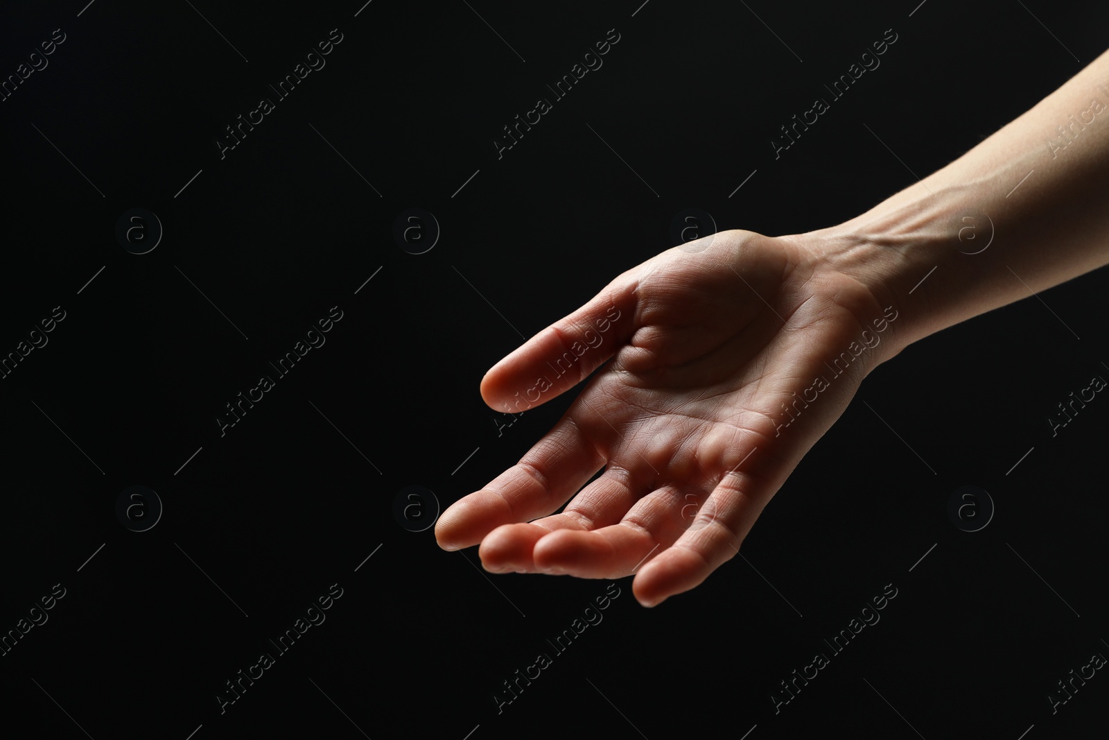 Photo of Woman holding something in hand on black background, closeup. Space for text