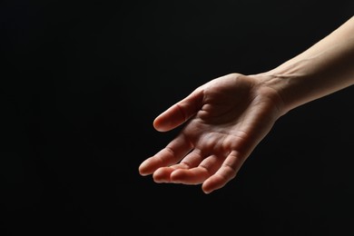 Photo of Woman holding something in hand on black background, closeup. Space for text