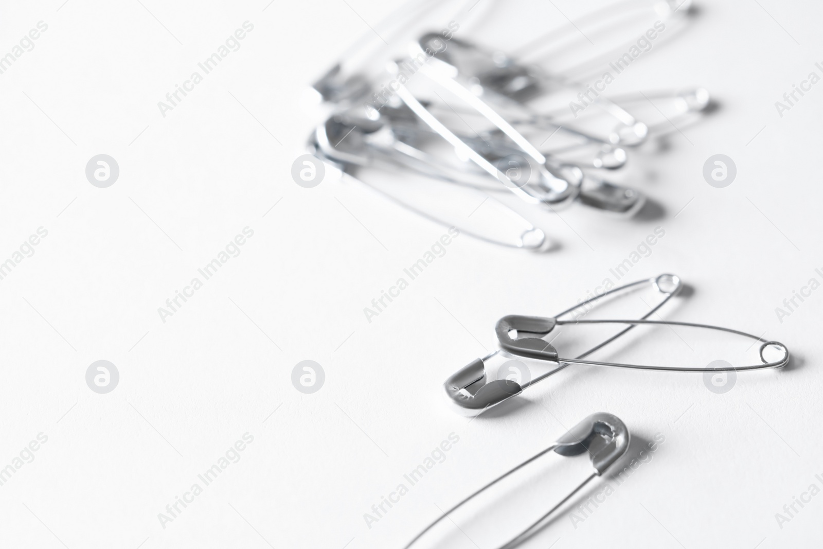 Photo of Many safety pins on white background, space for text