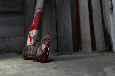 Photo of Axe with blood on floor indoors, closeup. Space for text