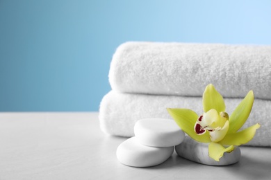Photo of Spa stones, towels and exotic flower on grey table, space for text