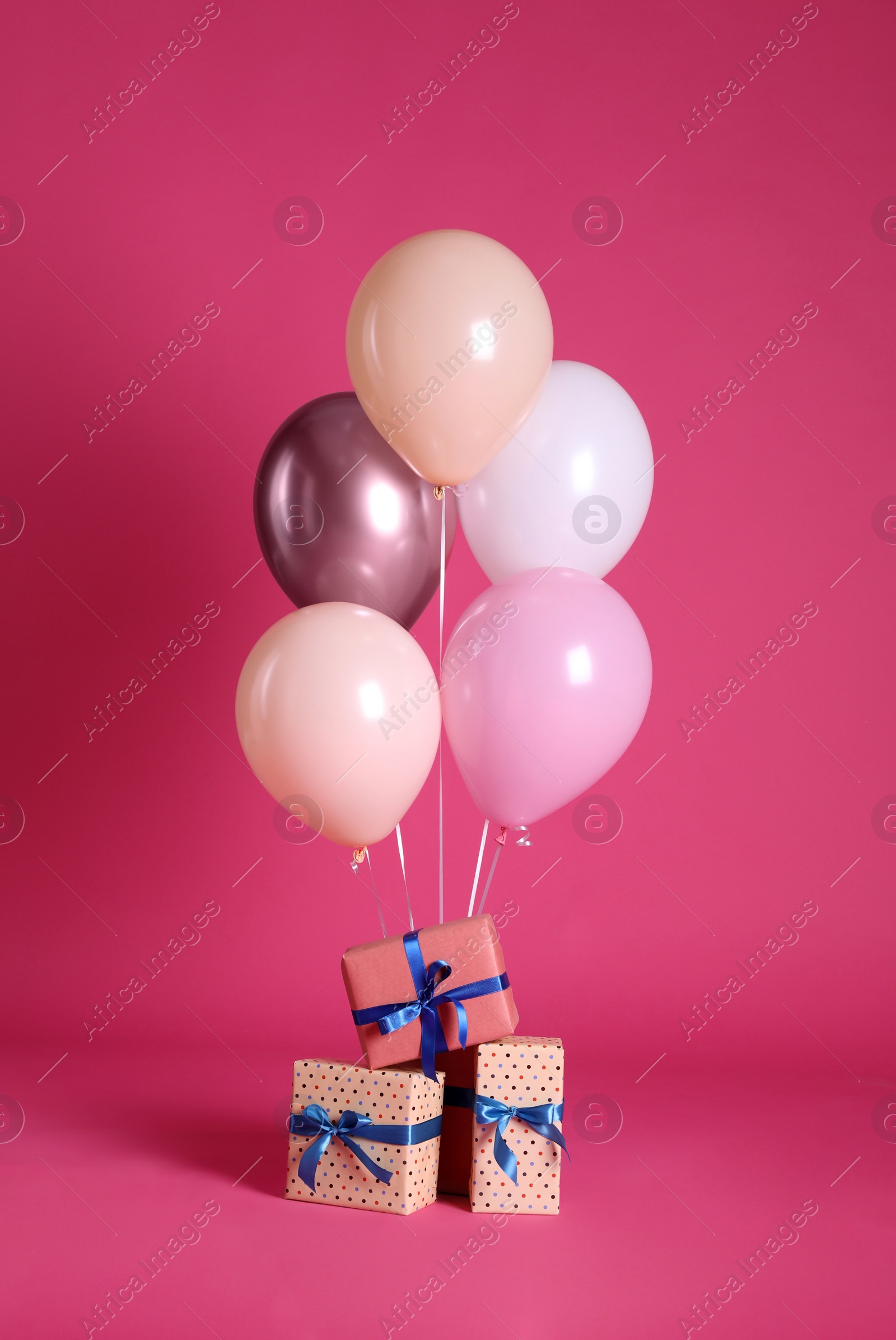 Photo of Gift boxes and balloons near bright pink ​background