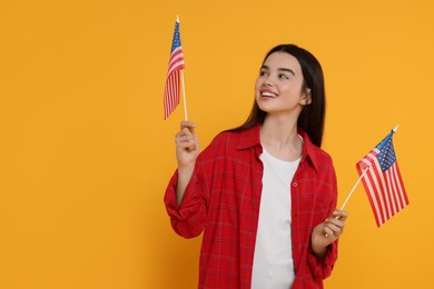 Photo of 4th of July - Independence Day of USA. Happy girl with American flags on yellow background, space for text