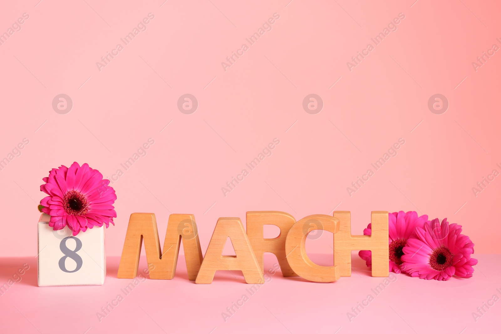 Photo of Women's Day composition with flowers and wooden letters on table against color background, space for text