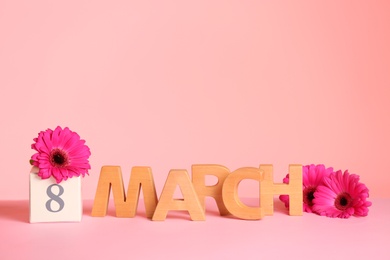 Photo of Women's Day composition with flowers and wooden letters on table against color background, space for text