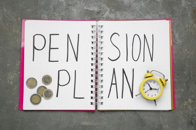 Photo of Notebook with words Pension Plan, coins and yellow small alarm clock on grey table, top view