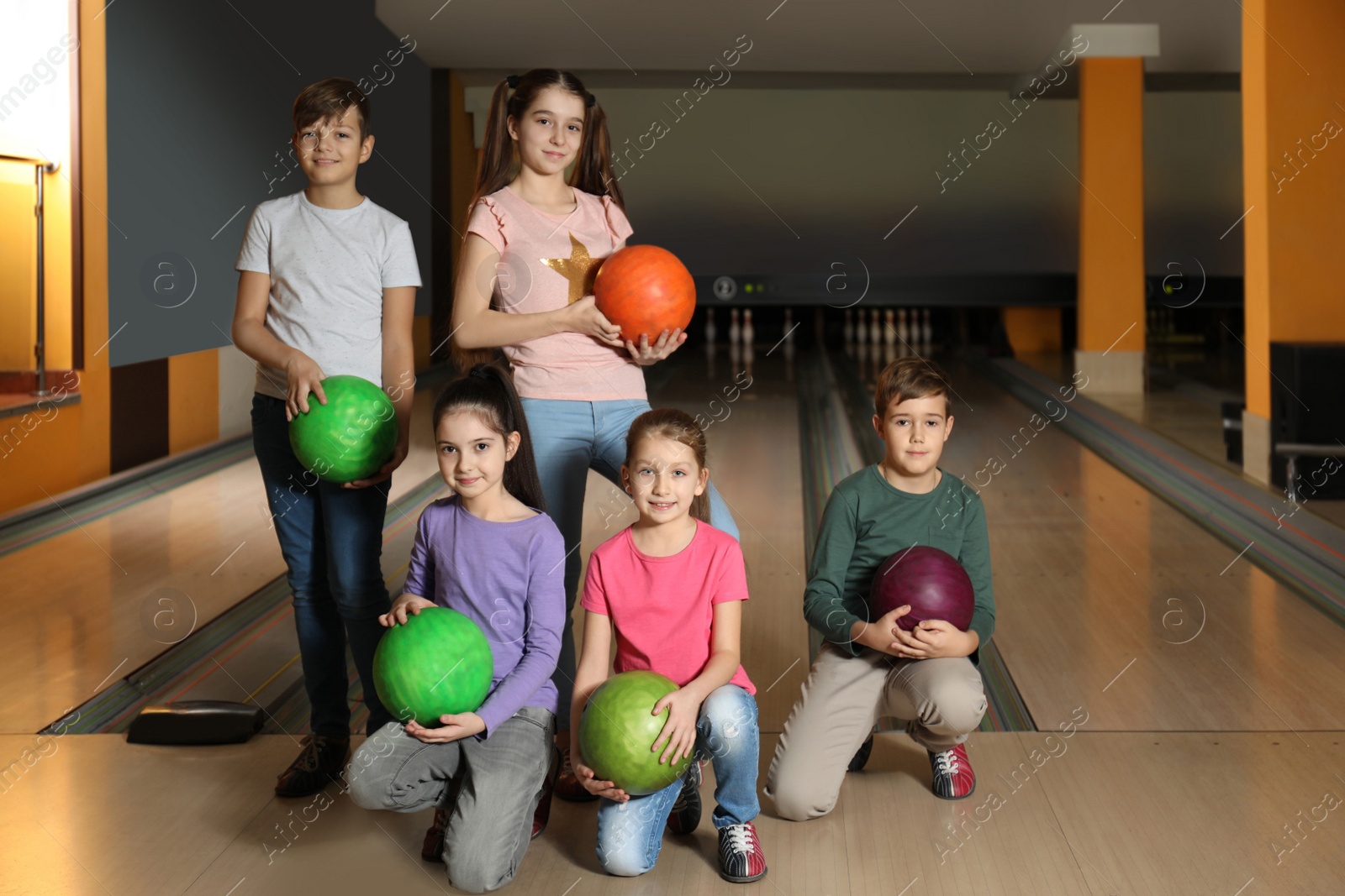 Photo of Happy children with balls in bowling club