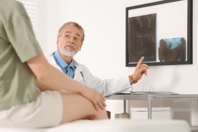 Photo of Orthopedist showing X-ray picture to patient in clinic