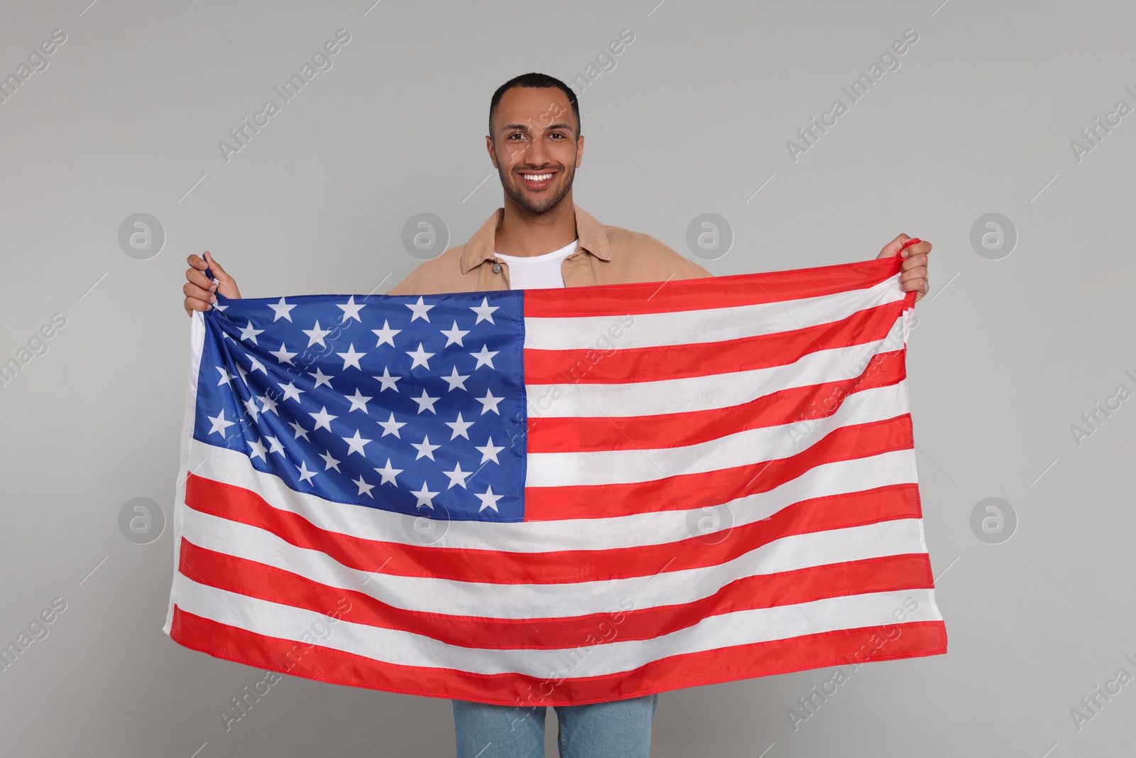 Photo of 4th of July - Independence Day of USA. Happy man with American flag on light grey background