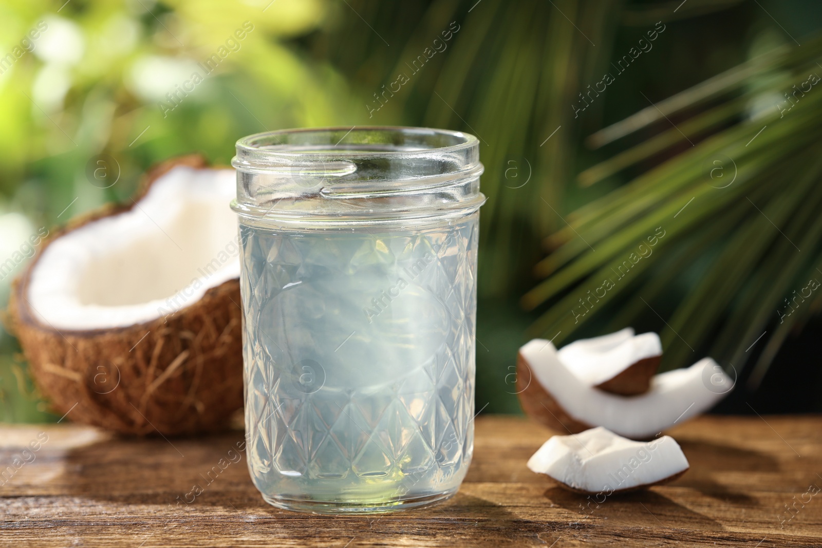 Photo of Coconut oil on wooden table against blurred background