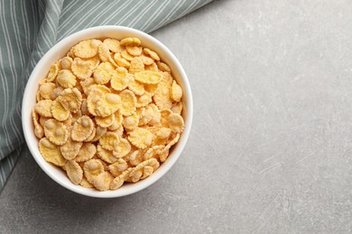 Photo of Bowl of tasty corn flakes on light grey background, top view. Space for text