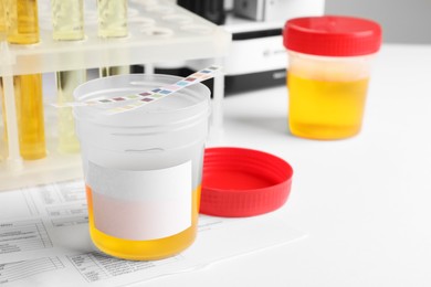 Photo of Container with urine sample on white table, space for text. Specimen collection