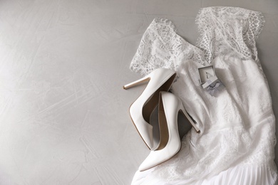 Wedding dress, white high heel shoes and ring on grey background, flat lay. Space for text