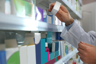 Image of Professional pharmacist with medicine in modern drugstore, closeup