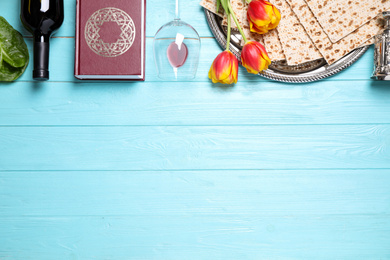 Photo of Flat lay composition with symbolic Pesach (Passover Seder) items on light blue wooden table, space for text