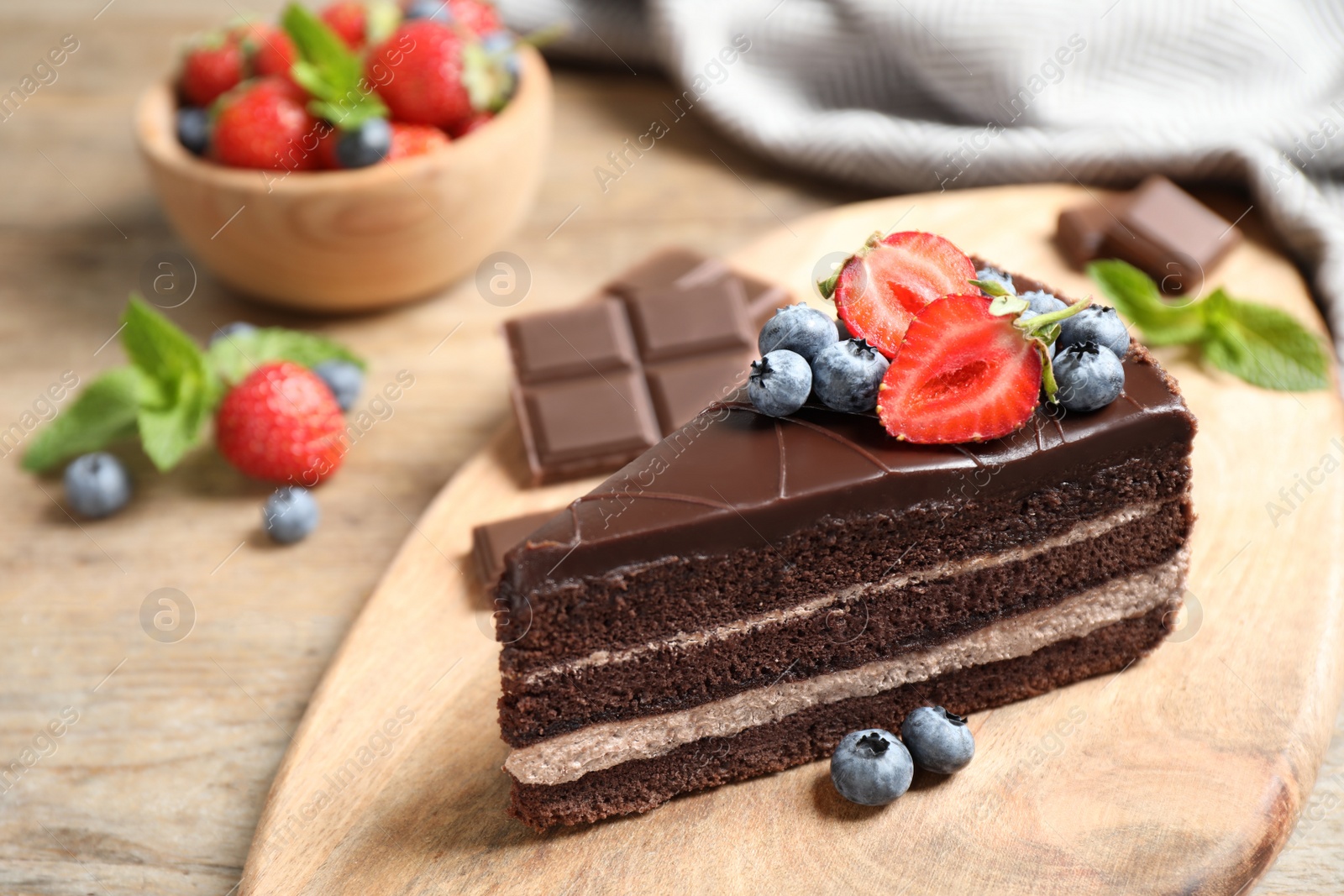 Photo of Delicious fresh chocolate cake with berries on wooden table