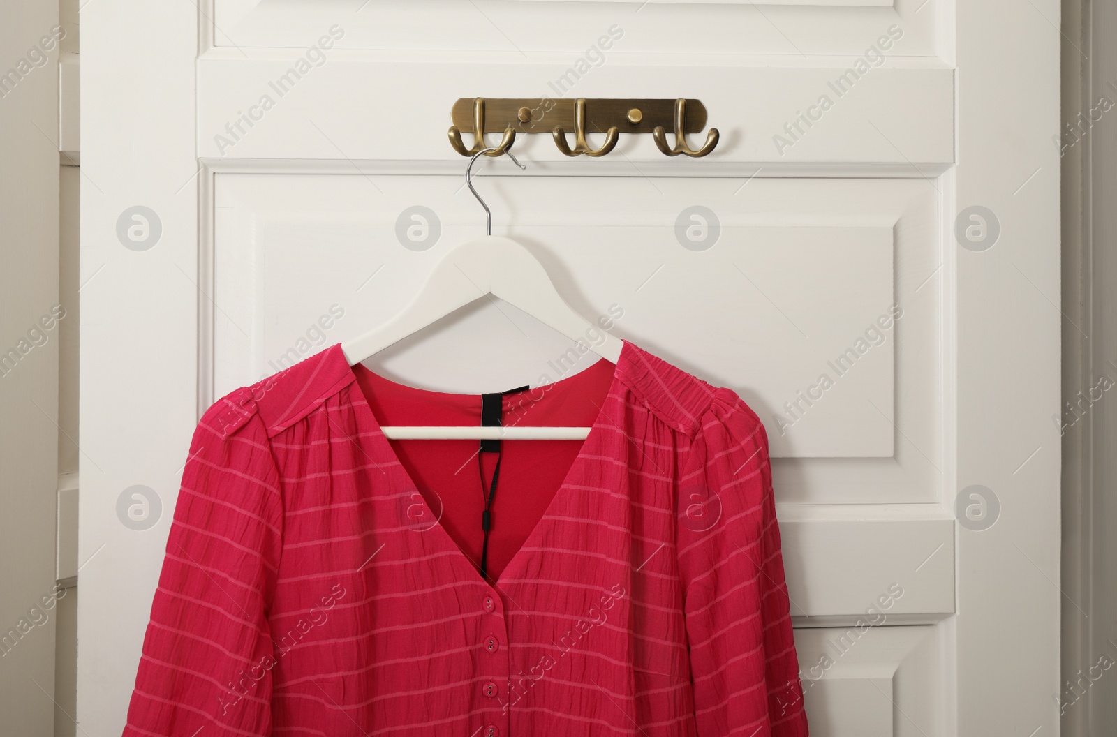 Photo of Hanger with beautiful blouse on white door