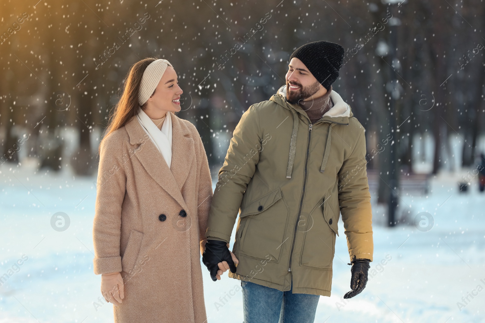 Photo of Beautiful happy couple walking in snowy park on winter day