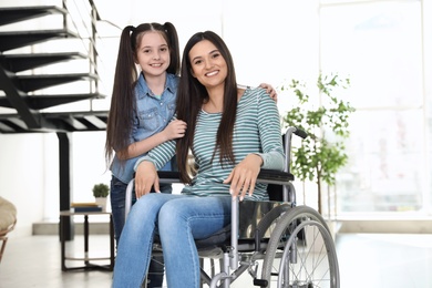 Young woman in wheelchair with her daughter indoors