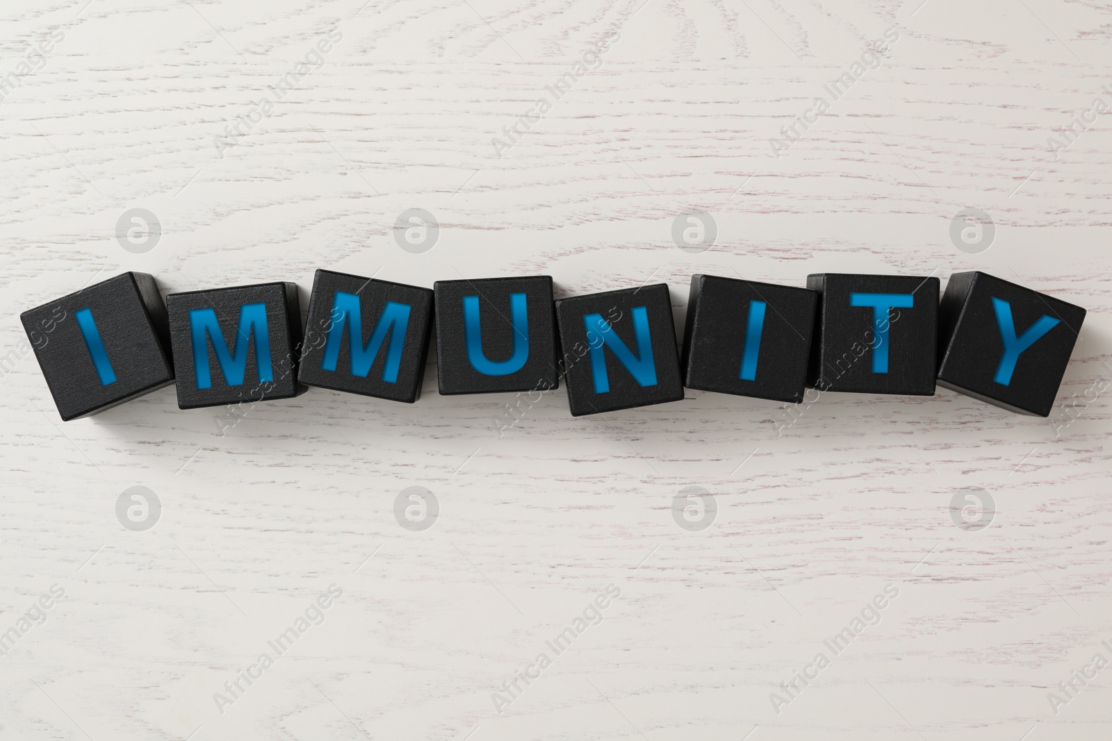 Photo of Black cubes with word Immunity on white wooden table, flat lay