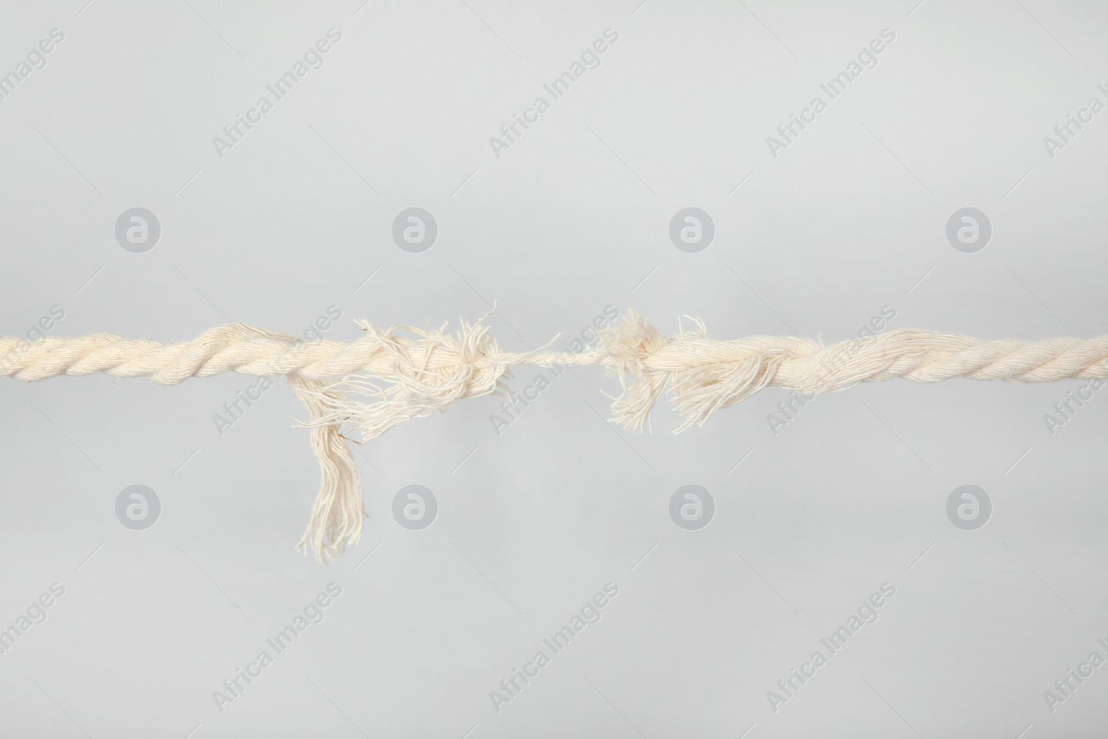 Photo of Frayed rope at breaking point on gray background