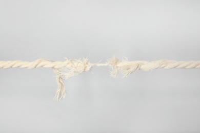 Photo of Frayed rope at breaking point on gray background