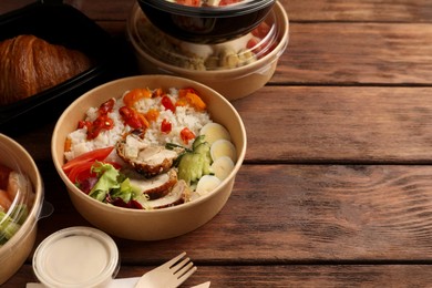 Tasty food in containers on wooden table, space for text