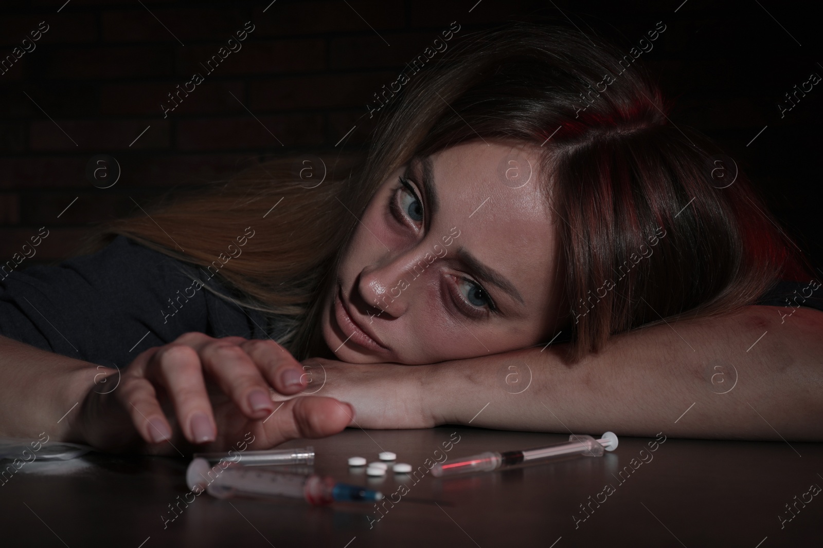 Photo of Addicted woman at table with different drugs