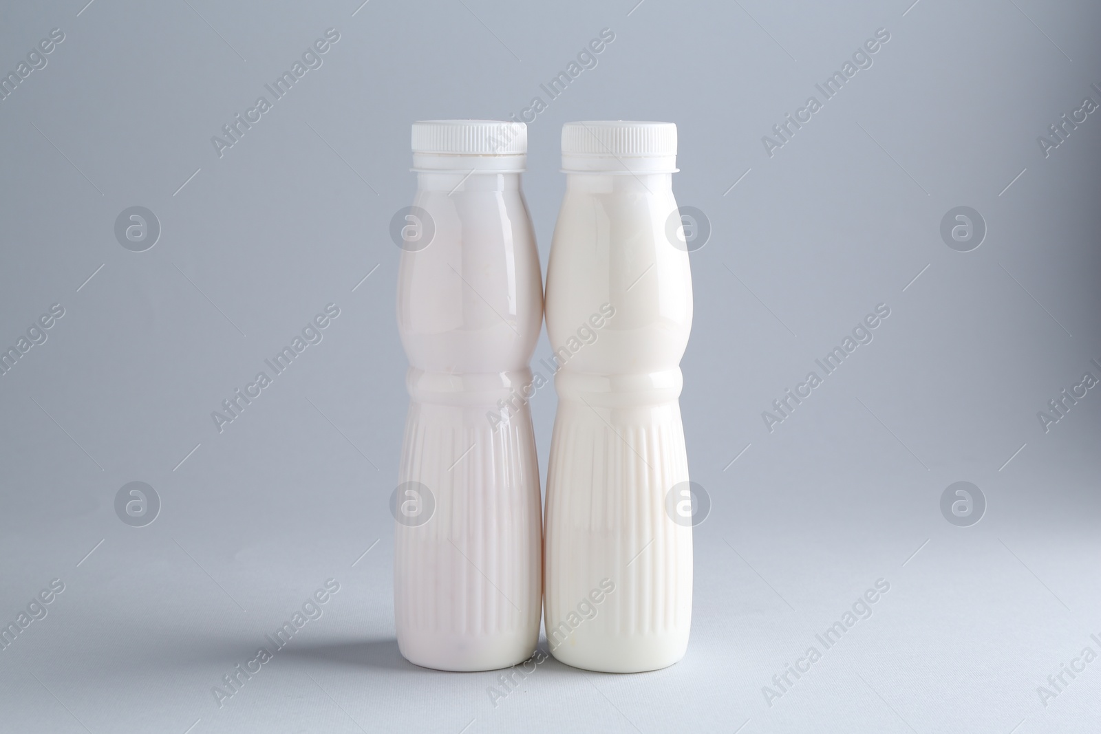 Photo of Tasty yogurt in bottles on light grey background