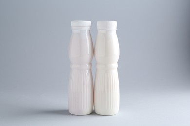 Tasty yogurt in bottles on light grey background