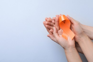 Photo of Couple holding orange ribbon on light grey background, top view with space for text. Multiple sclerosis awareness